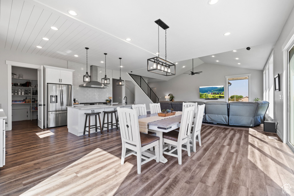 Dining space featuring ceiling fan with notable chandelier, lofted ceiling, sink, and dark hardwood / wood-style floors