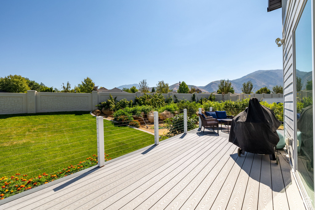 Wooden deck featuring area for grilling, a lawn, and a mountain view