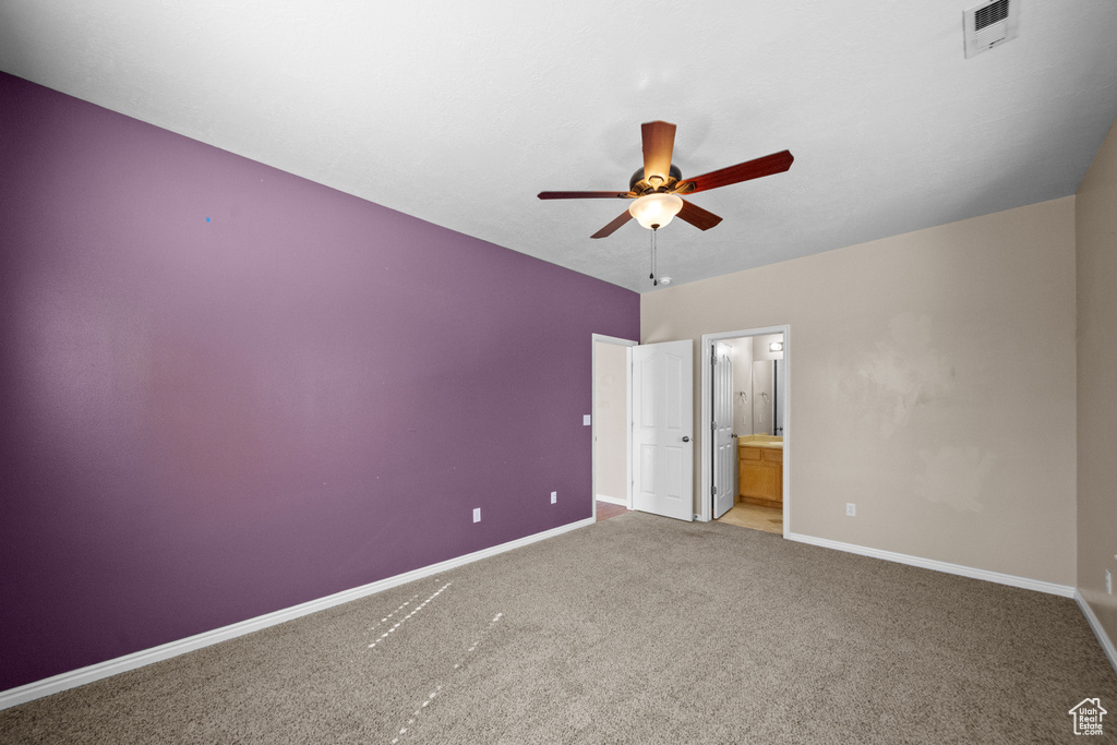 Unfurnished bedroom with ceiling fan, connected bathroom, and light colored carpet