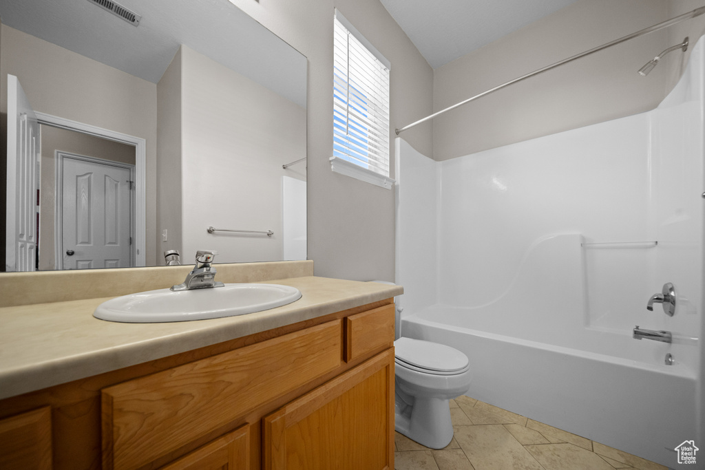 Full bathroom featuring tile patterned flooring, toilet, vanity, and shower / tub combination