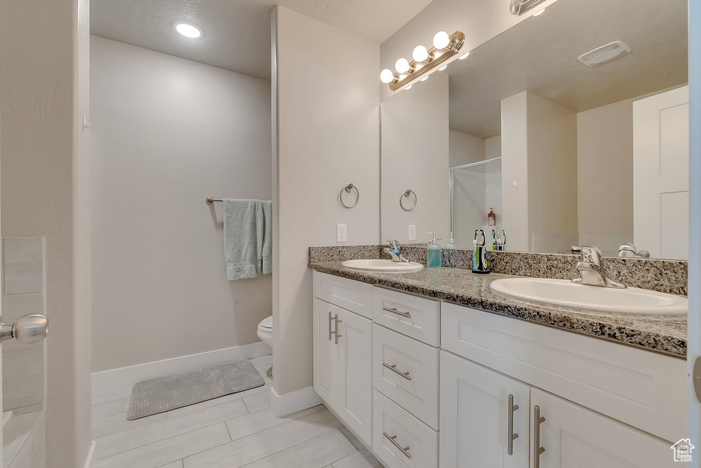 Bathroom with toilet, a shower, vanity, and tile patterned floors