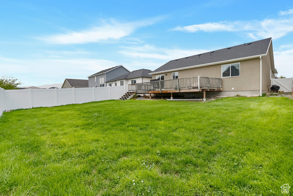 Rear view of house with a wooden deck and a yard