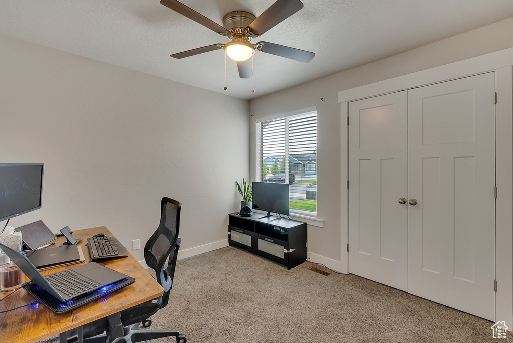 Home office featuring ceiling fan and light carpet