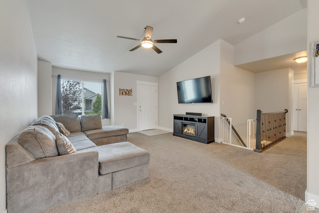 Living room featuring carpet, a fireplace, high vaulted ceiling, and ceiling fan