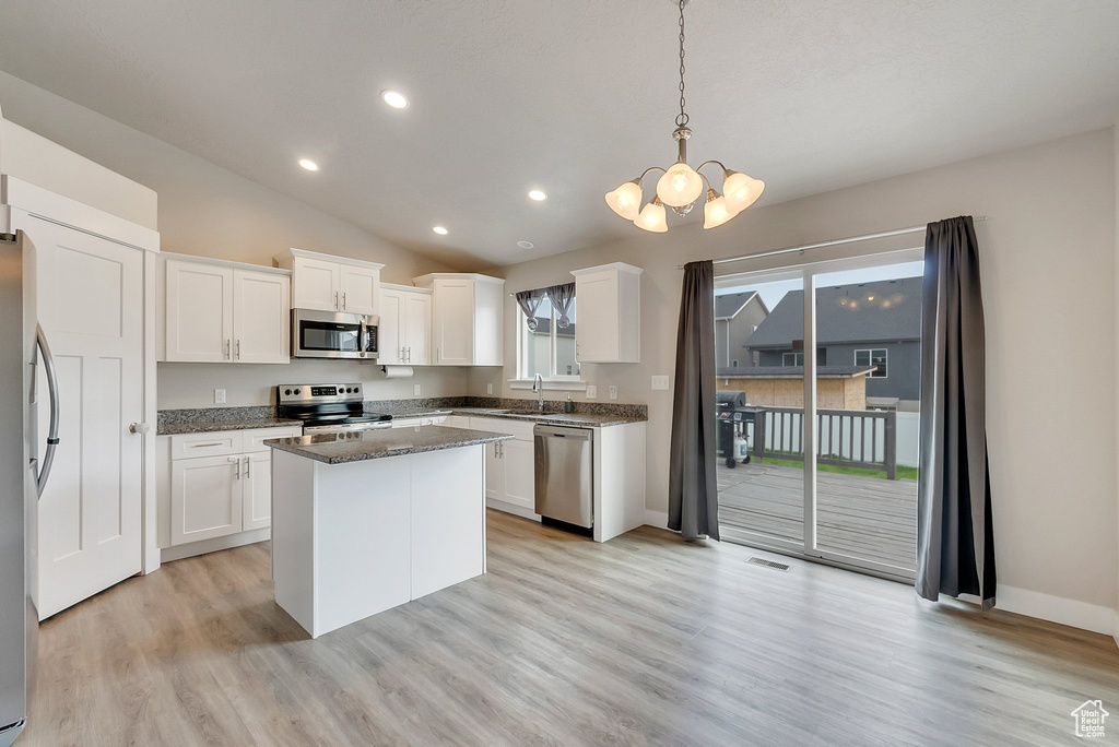 Kitchen with dark stone counters, light hardwood / wood-style flooring, white cabinetry, and stainless steel appliances