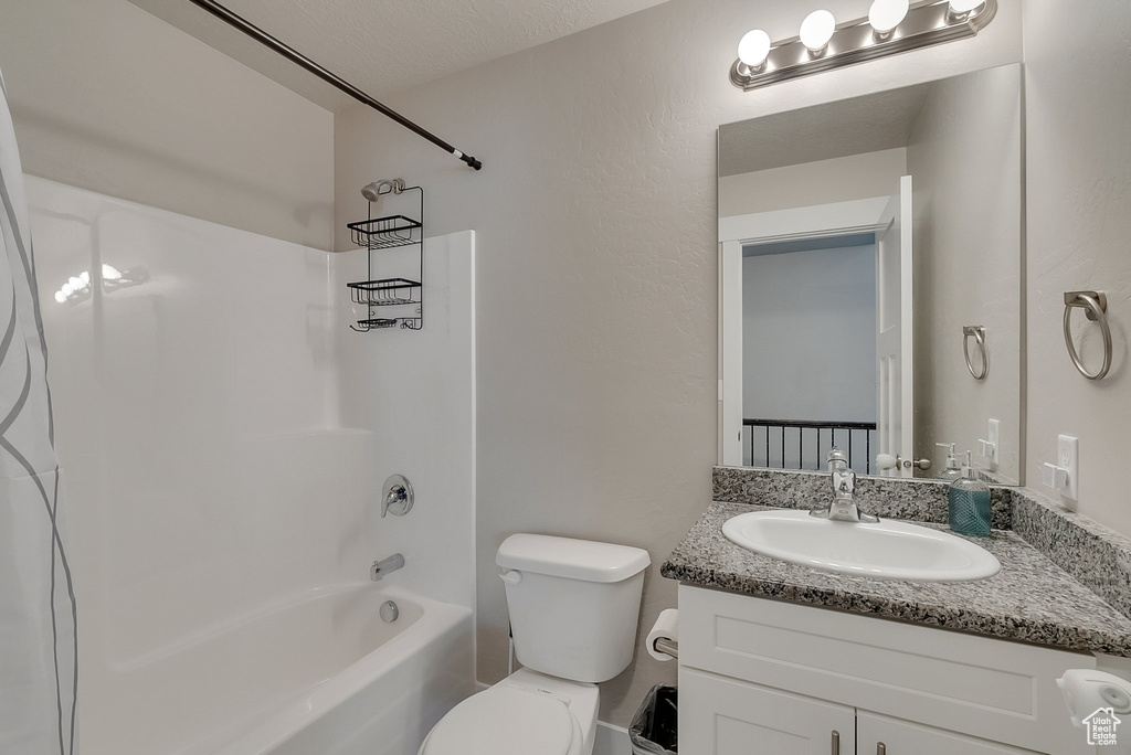 Full bathroom featuring a textured ceiling, bathtub / shower combination, vanity, and toilet