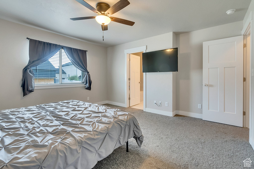 Carpeted bedroom featuring ceiling fan and ensuite bath