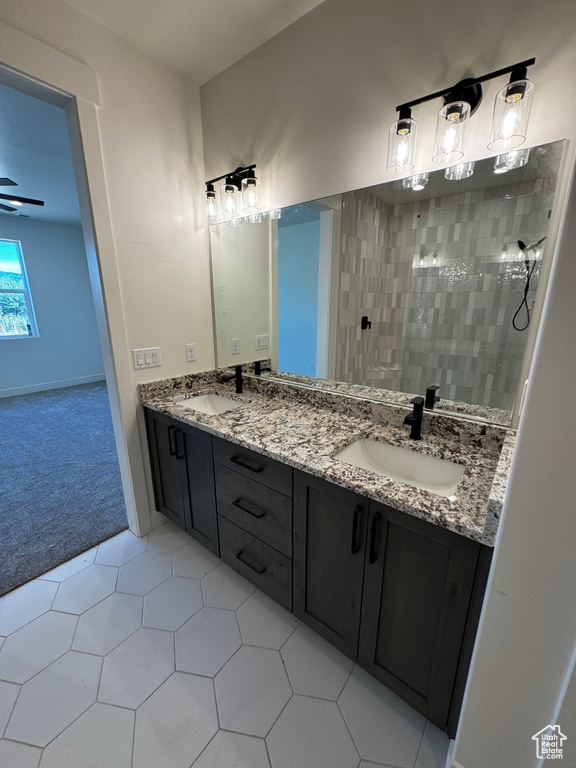 Bathroom with tile patterned flooring, a tile shower, and vanity