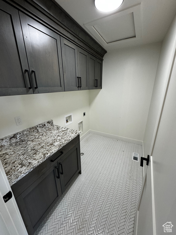 Washroom with light tile patterned floors, cabinets, and hookup for an electric dryer