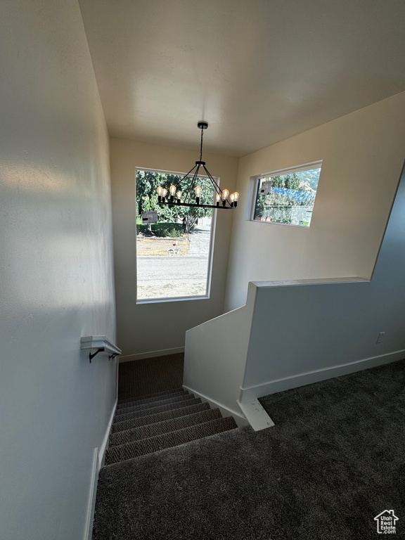 Stairway featuring carpet and a chandelier