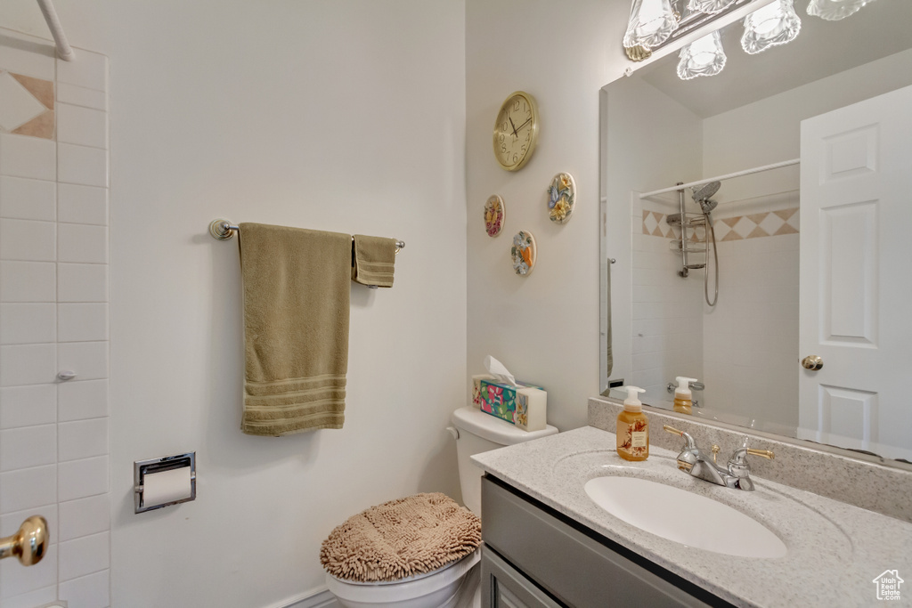 Bathroom with toilet, vanity, and tiled shower