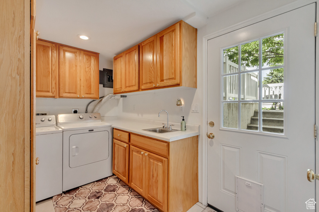 Washroom with sink, washer and clothes dryer, light tile patterned floors, and cabinets