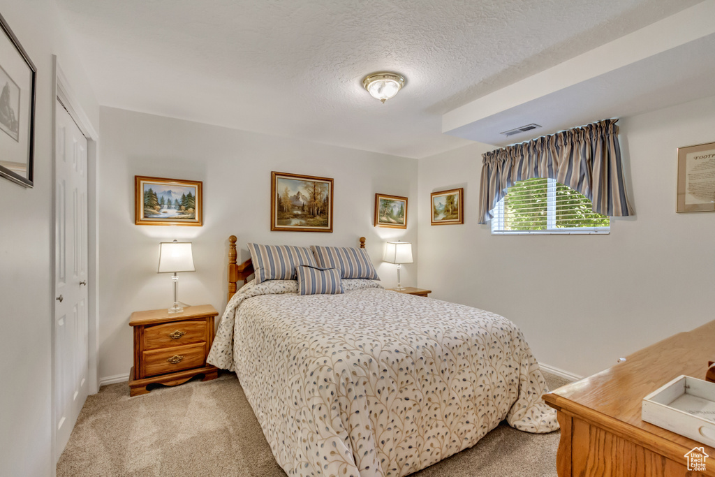 Carpeted bedroom featuring a textured ceiling and a closet