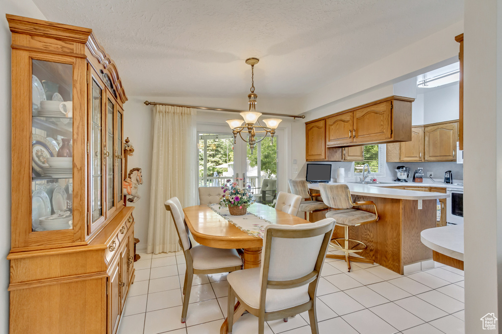 Tiled dining space featuring sink and an inviting chandelier