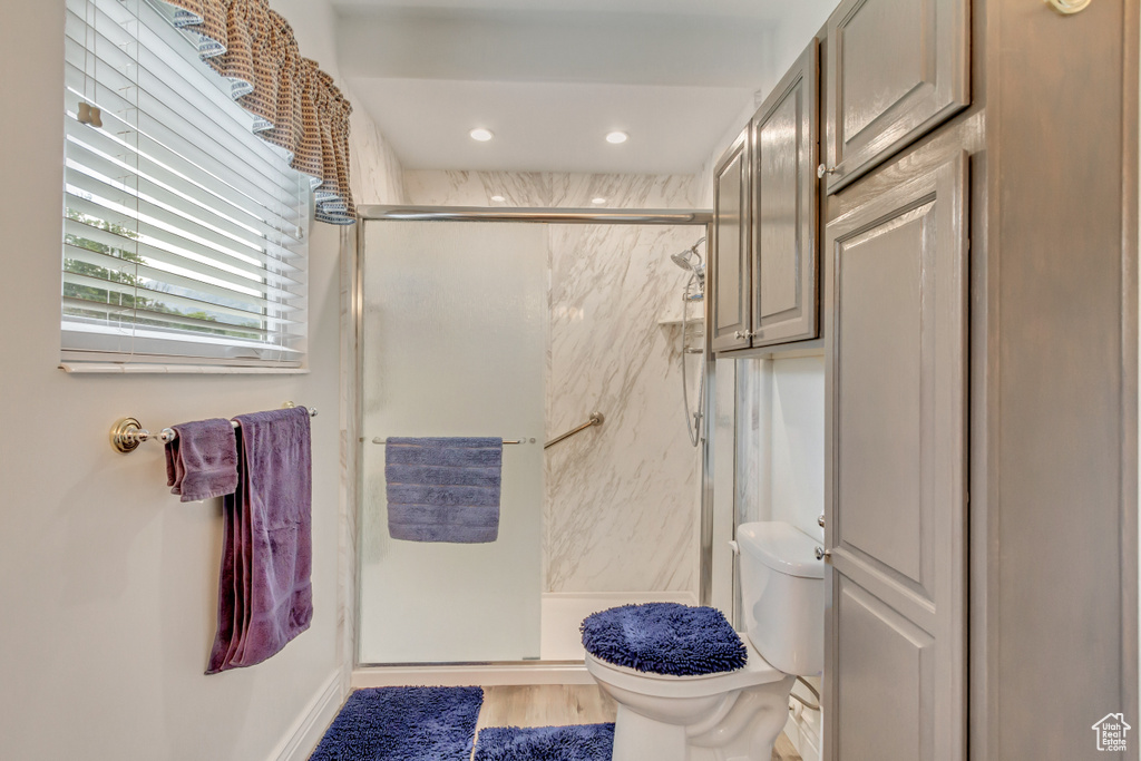 Bathroom featuring hardwood / wood-style flooring, a shower with shower door, and toilet