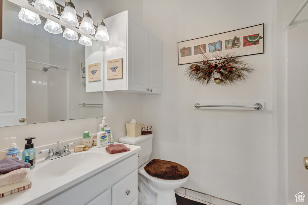 Bathroom featuring a shower, tile patterned flooring, vanity, and toilet