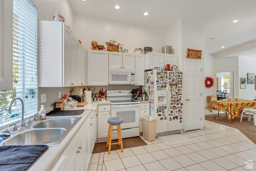 Kitchen with sink, white cabinetry, white appliances, and light tile patterned floors