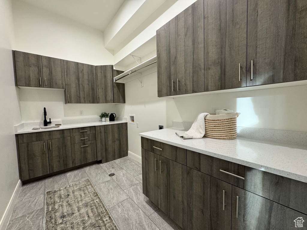 Kitchen with dark brown cabinetry, light stone countertops, and sink