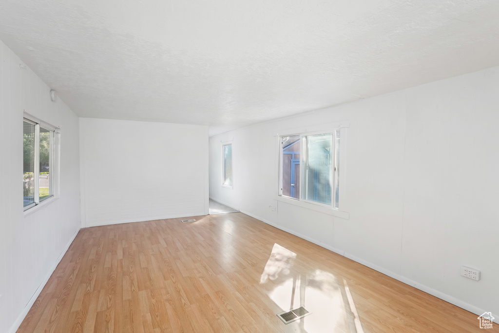 Empty room featuring light wood-type flooring and a textured ceiling