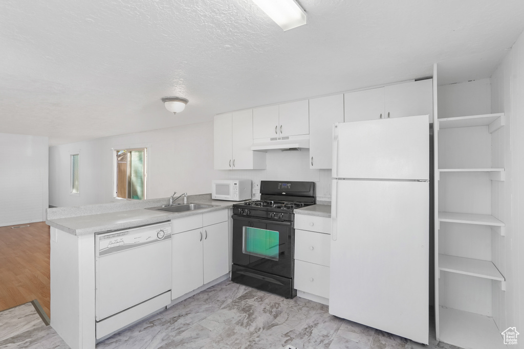 Kitchen with white cabinets, sink, kitchen peninsula, light tile patterned flooring, and white appliances