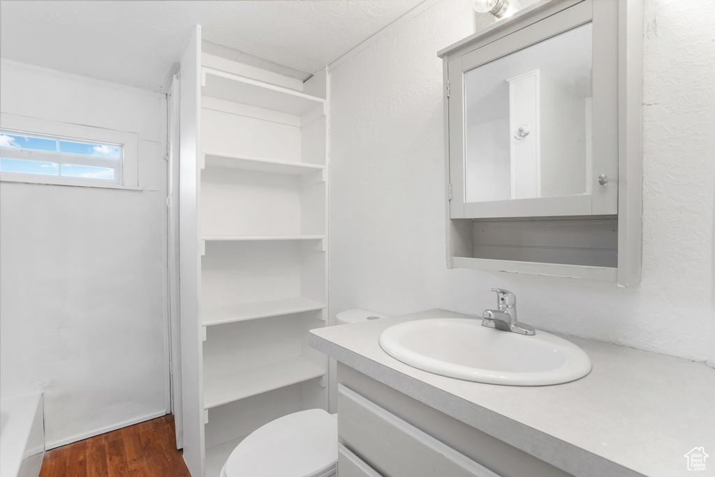 Full bathroom featuring toilet, shower with separate bathtub, vanity, and wood-type flooring