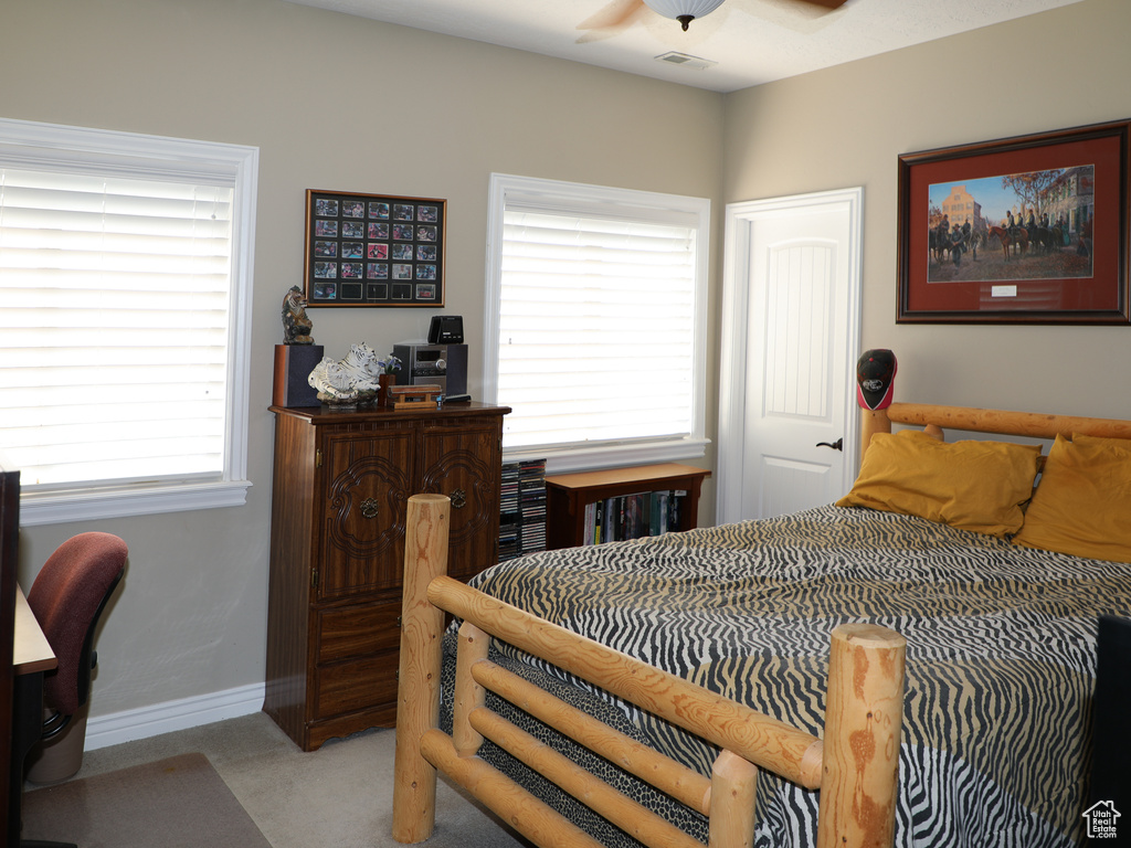 Carpeted bedroom featuring ceiling fan and multiple windows