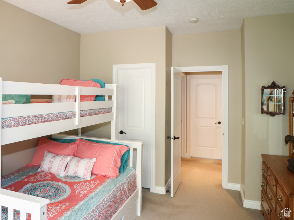 Bedroom featuring a textured ceiling, light colored carpet, and ceiling fan