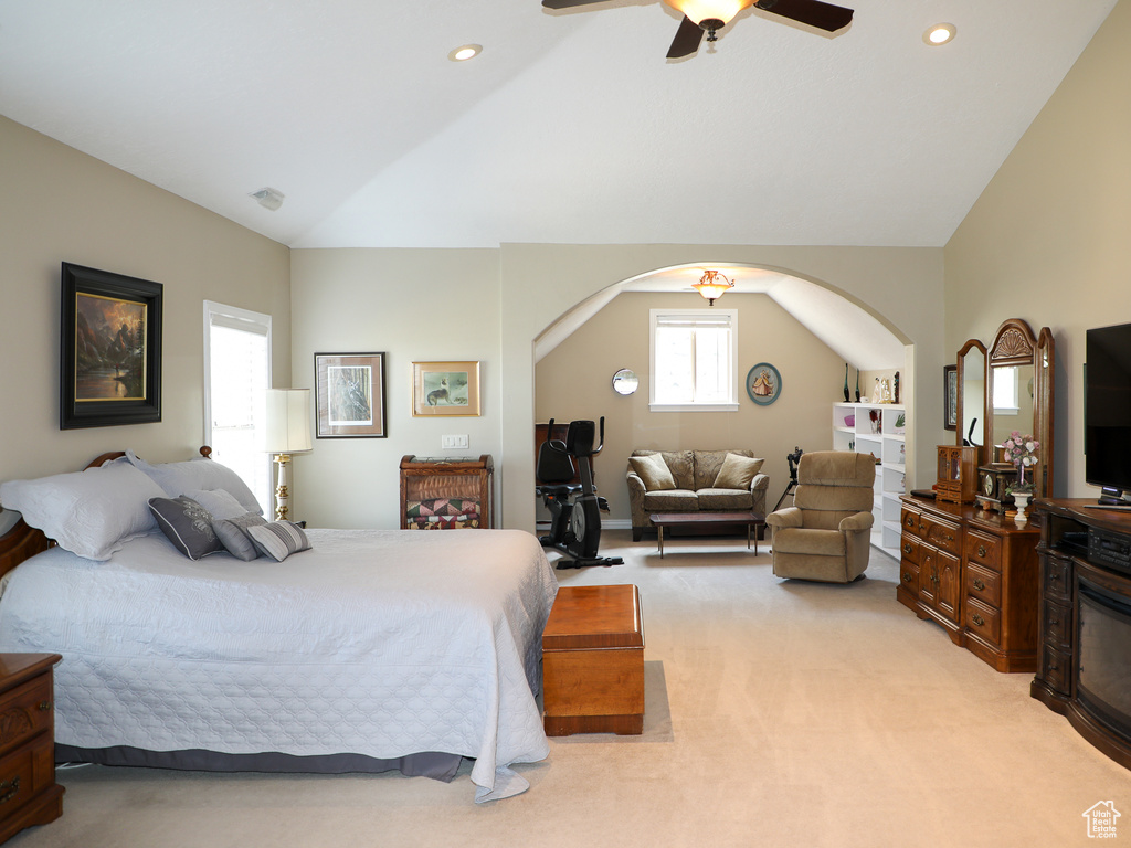 Carpeted bedroom with ceiling fan, multiple windows, and vaulted ceiling