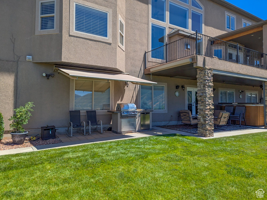 Rear view of property with a balcony, a yard, and a patio