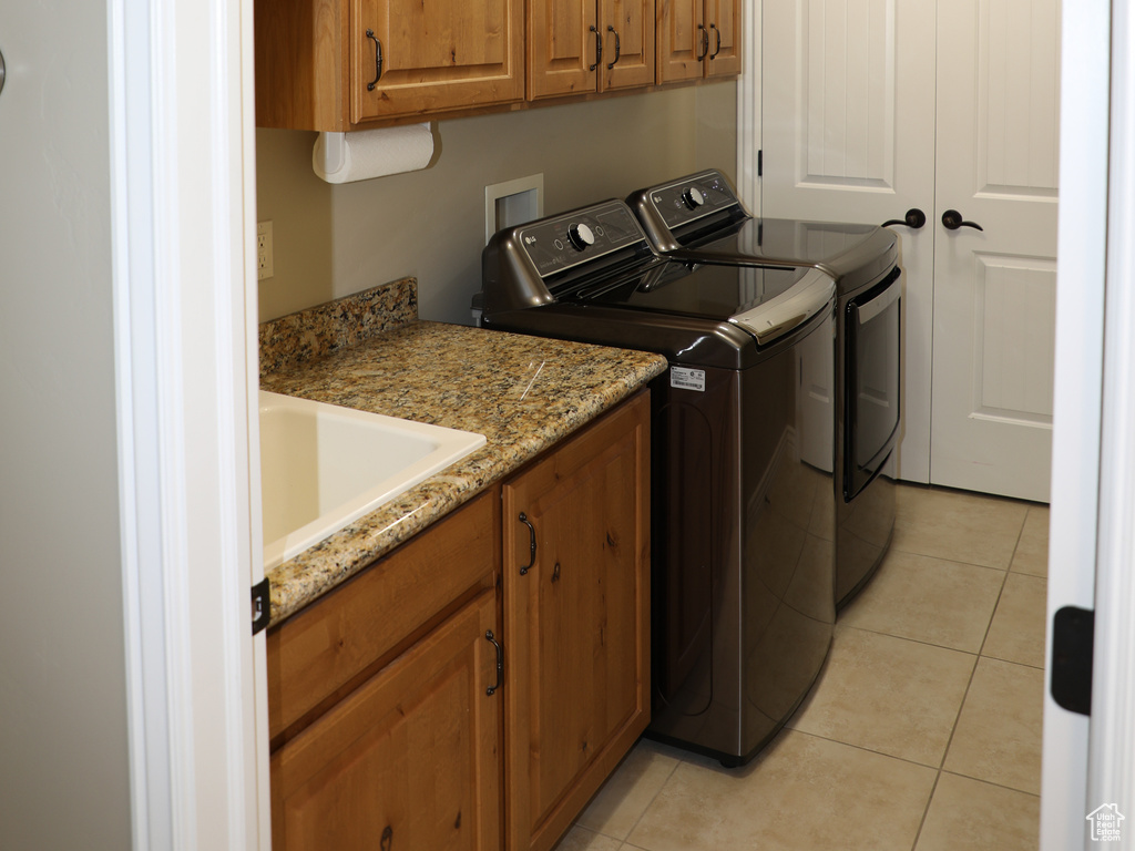 Washroom featuring independent washer and dryer, light tile patterned floors, sink, and cabinets