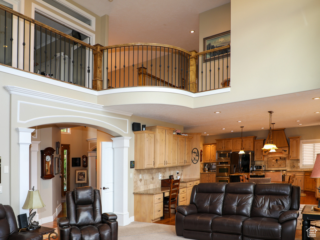 Living room with light hardwood / wood-style floors, decorative columns, and a towering ceiling