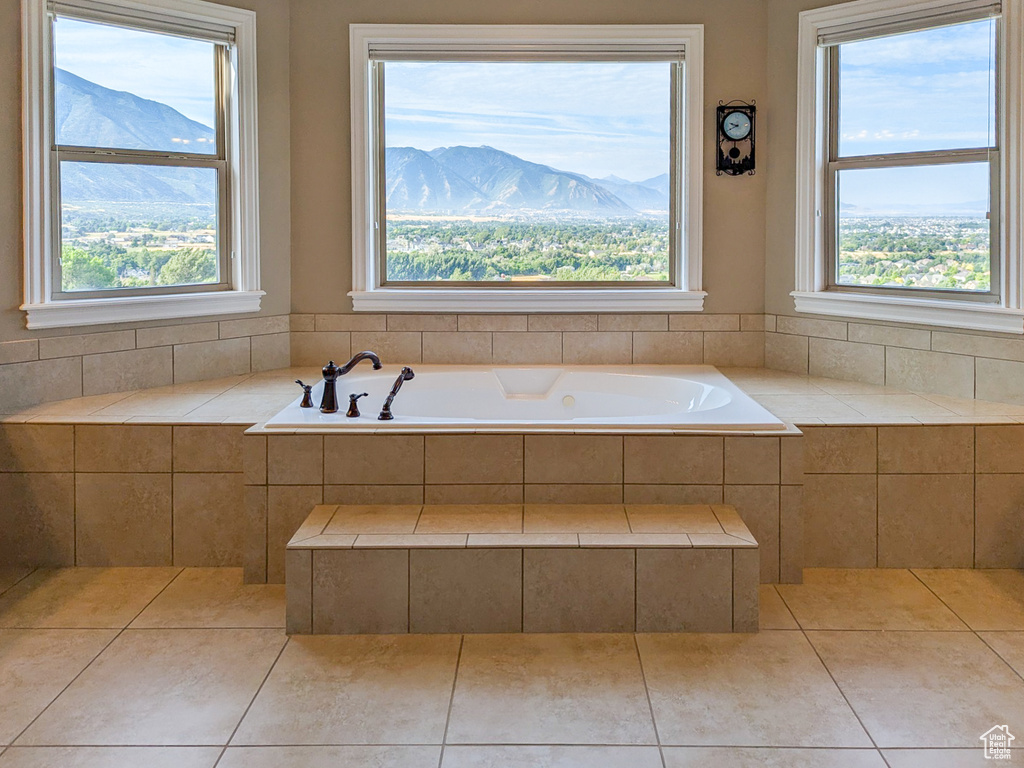 Bathroom with a mountain view, a relaxing tiled tub, and a healthy amount of sunlight