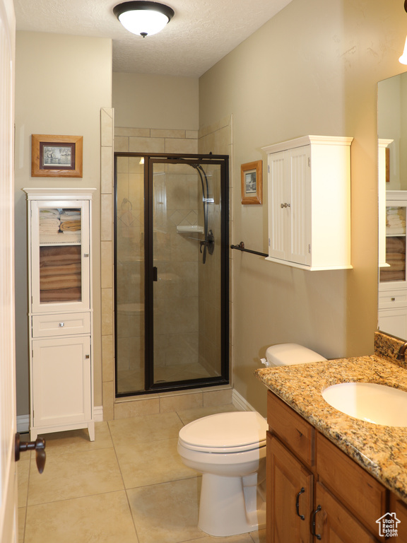 Bathroom with tile patterned floors, vanity, walk in shower, and toilet