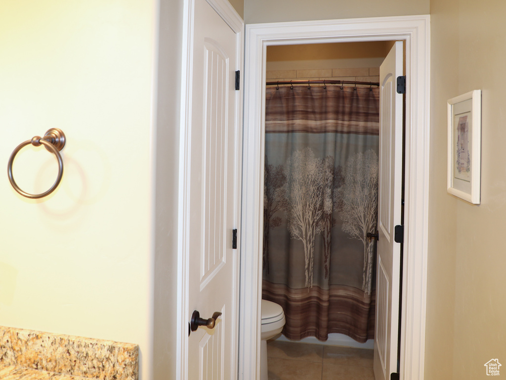 Bathroom featuring toilet, tile patterned flooring, and a shower with curtain