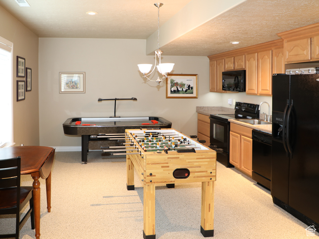 Kitchen featuring sink, an inviting chandelier, light brown cabinets, hanging light fixtures, and black appliances