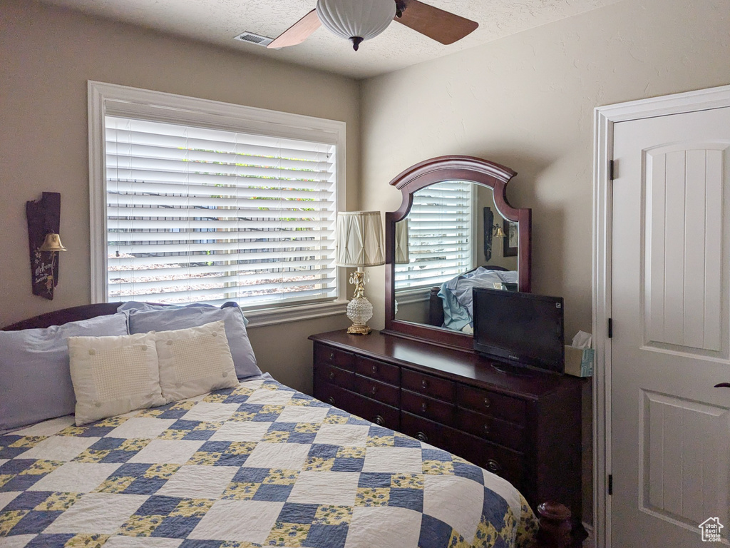 Bedroom with ceiling fan and a textured ceiling