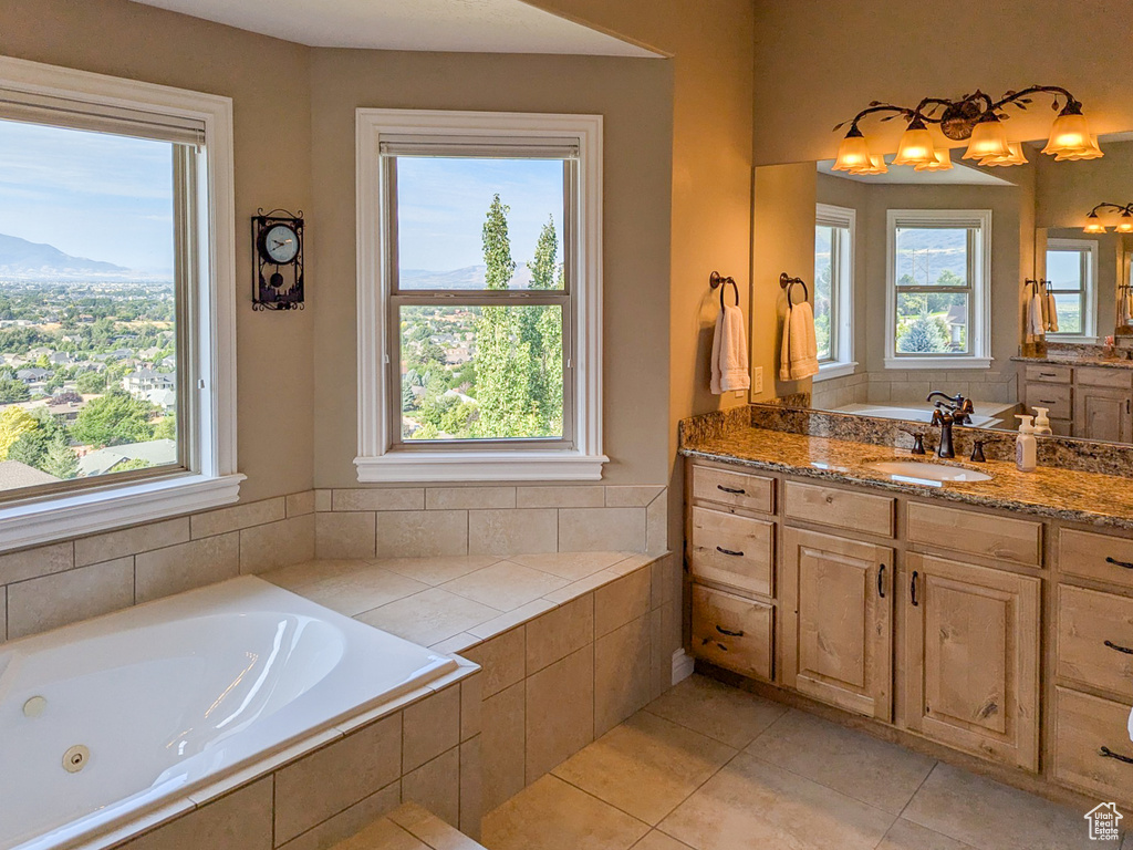 Bathroom with tiled bath, tile patterned floors, and vanity