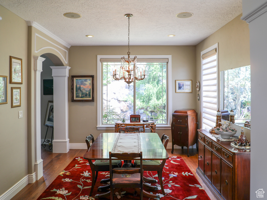 Dining space with a wealth of natural light, a textured ceiling, hardwood / wood-style flooring, and decorative columns