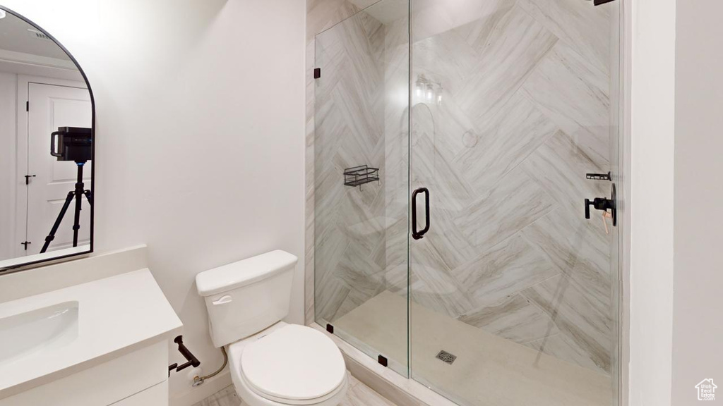 Bathroom with a shower with shower door, toilet, and vanity