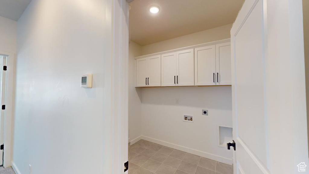 Washroom featuring washer hookup, cabinets, light tile patterned floors, and electric dryer hookup