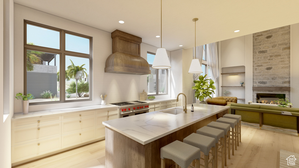 Kitchen featuring light wood-type flooring, high end stainless steel range oven, sink, and decorative light fixtures