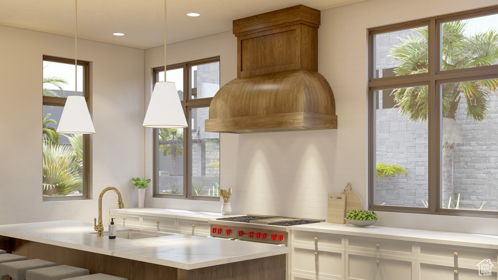 Kitchen featuring hanging light fixtures, white cabinetry, sink, and plenty of natural light