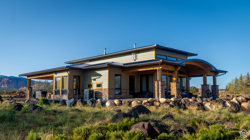 Rear view of property with cooling unit, stone siding, and a mountain view