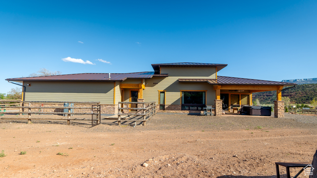 Back of property with a standing seam roof, metal roof, and stone siding