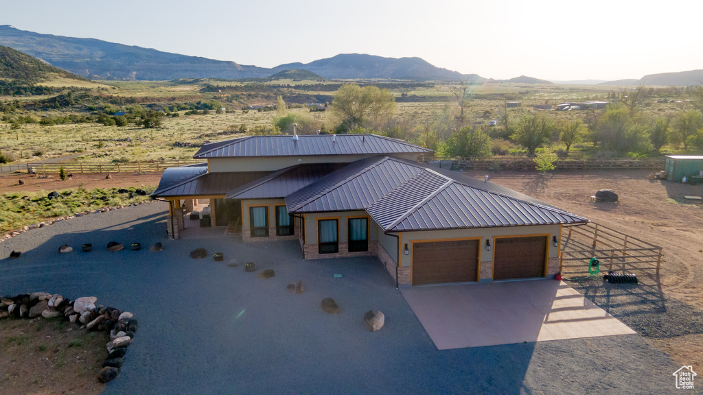 View of front of house with a mountain view, metal roof, fence, a garage, and concrete driveway