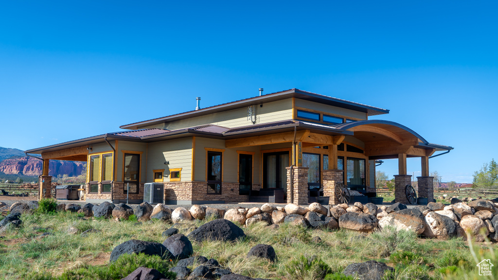 Back of house featuring central AC, metal roof, a mountain view, and stone siding