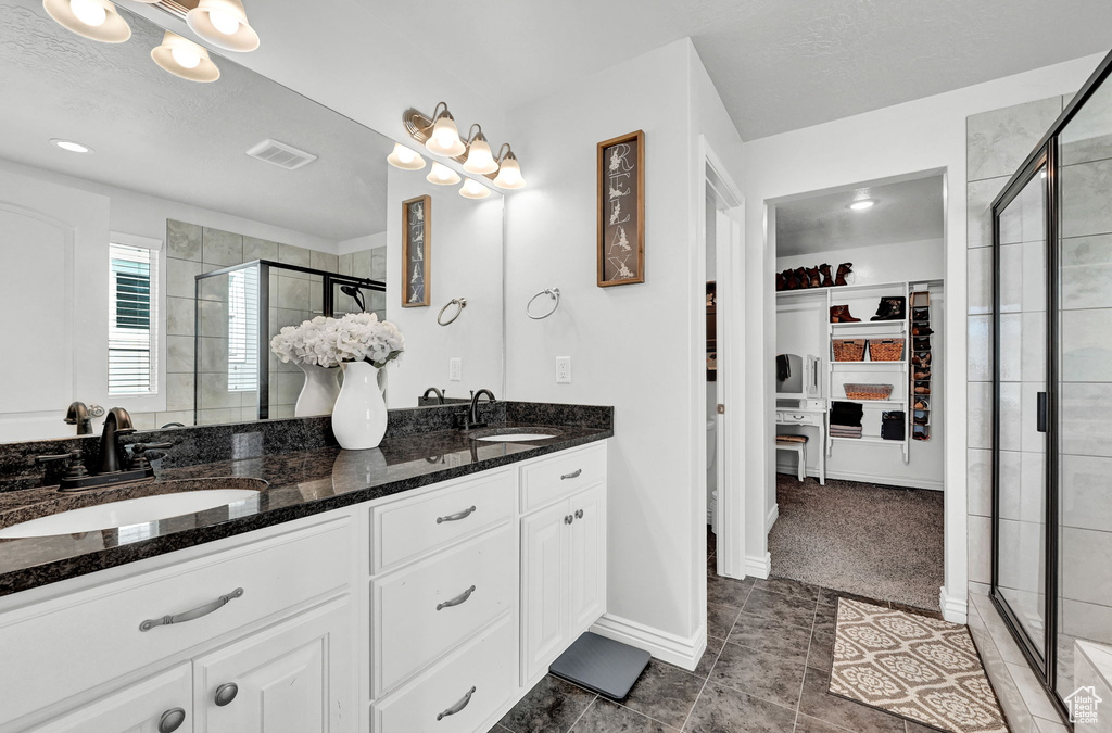 Bathroom featuring a shower with door, vanity, and tile patterned floors