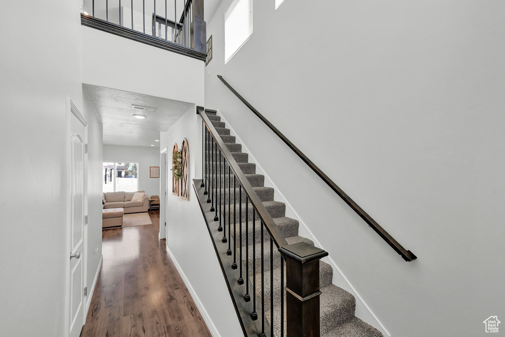 Staircase featuring a towering ceiling and hardwood / wood-style flooring