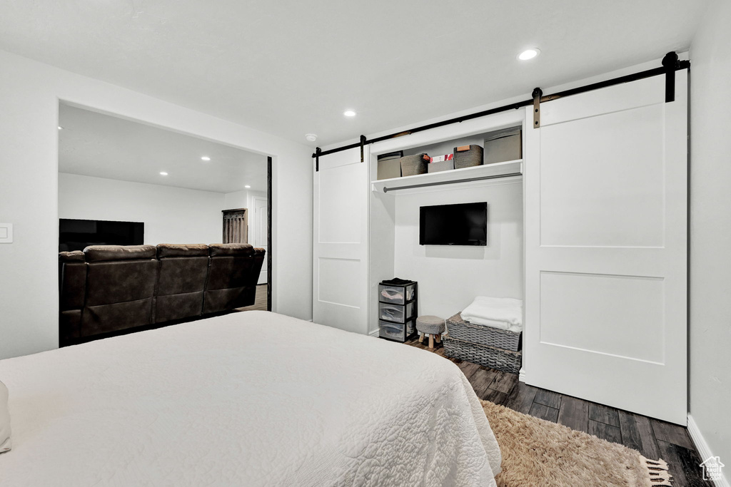 Bedroom featuring a barn door and dark wood-type flooring