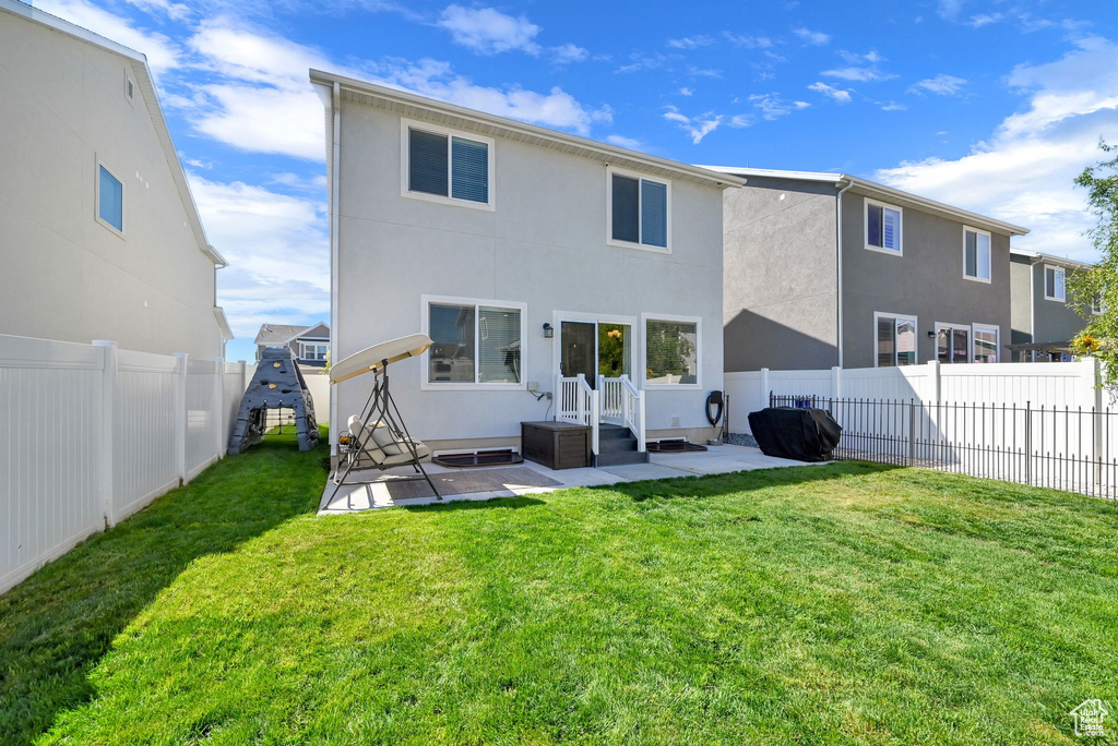 Rear view of property featuring a lawn and a patio